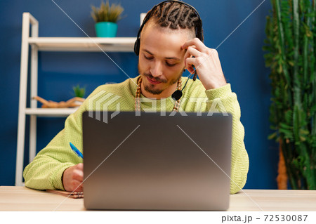Young man with headset looking at laptop camera. Service consultant concept Young man with headset looking at laptop camera. Service consultant concept 72530087
