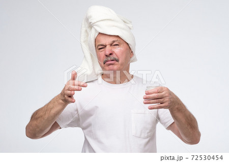 Mature man using cream for face skin having disgust expression. Mature man using cream for face skin having disgust expression. 72530454