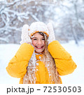 Outdoor portrait of young smiling girl, wearing yellow jacket in winter park 72530503