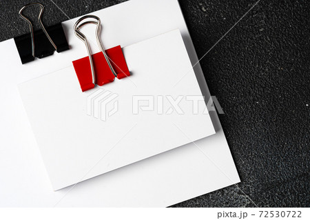 White businesscards united with a paper clip on a black rough background 72530722