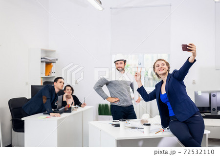 Employees having fun in the office, posing and taking selfies wi 72532110