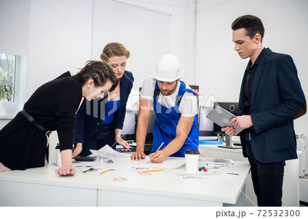 A creative team of business people at the meeting in the conference room. Two successful businesswomen and two businessmen around the desk, discussing new projects 72532300