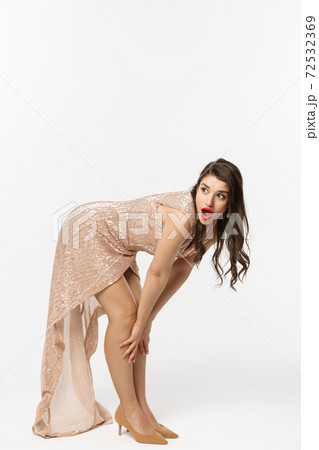 Christmas party and celebration concept. Full length of sensual brunette in luxury dress, bend down and looking left with surprised face, white background 72532369