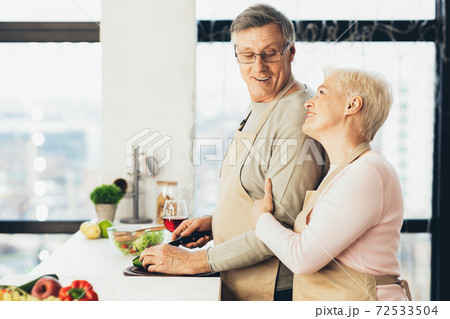 Elderly Couple Cooking Making Salad For Dinner In Kitchen, Side-View Elderly Couple Cooking Making Salad For Dinner In Kitchen, Side-View 72533504