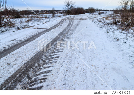 Tire tracks on icy road covered with snow 72533831