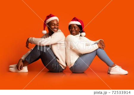 Romantic Black Couple In Santa Hats Sitting And Turning At Each Other Romantic Black Couple In Santa Hats Sitting And Turning At Each Other 72533914