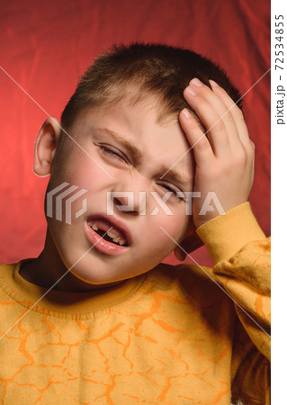 The little boy shows headache and gestures with his hands, resting them on his head. The little boy shows headache and gestures with his hands, resting them on his head. 72534855