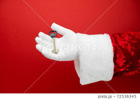 Santa Claus hand holds house key. Success, happiness, dream, december, mortgage, ownership, property, purchase, real estate, rent, sale, sell, accommodation, apartment concept.  72536345