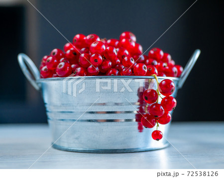 A metal basin filled with red currants 72538126