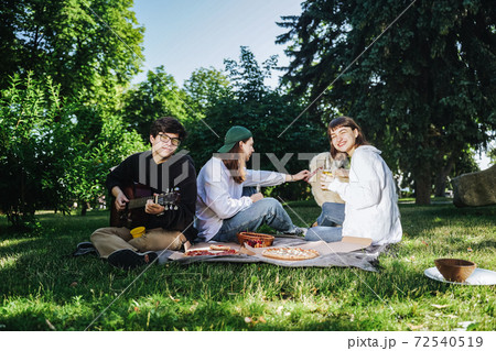 Company of beautiful young people and dog having an outdoor lunch. Company of beautiful young people and dog having an outdoor lunch. 72540519