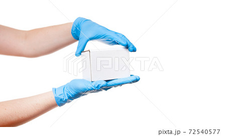 Delivery man hands in blue sterile gloves holds white label cardboard box, safe delivery during quarantine stay home, concept banner on medical theme isolated on white background with copy space. 72540577
