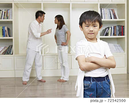 six-year old asian boy with quarreling parents in background. six-year old asian boy with quarreling parents in background. 72542500