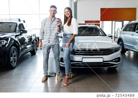 Young happy couple just bought a new car in a dealership 72543489