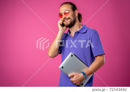 Man in glasses standing with laptop against pink background 72543692