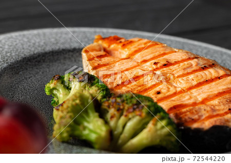 Grilled salmon steak with broccoli on grey plate 72544220