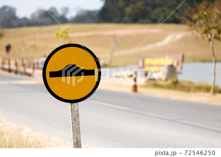 Black speed bump sign on yellow background on roadside. Black speed bump sign on yellow background on roadside. 72546250