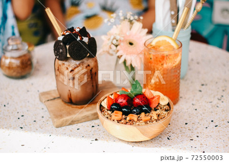 Healthy breakfast bowl with fresh berries, nuts, bananas and chocolate smoothie drink. Vegan food. Healthy breakfast bowl with fresh berries, nuts, bananas and chocolate smoothie drink. Vegan food. 72550003