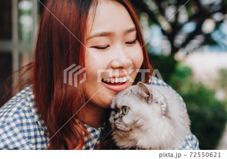 Close up of young Asian woman playing with her persian cat, human-animal relationships. 72550621