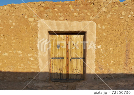 North African-style wooden door to the wall of a ruined stone 72550730