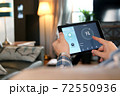 Man is Adjusting a temperature using a tablet with smart home app in modern living room 72550936