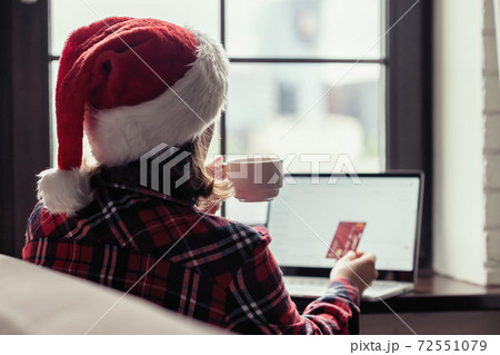 Back view of lonely european young woman wrapped in a plaid with with alarm clock sitting near window at cold winter day. Back view of lonely european young woman wrapped in a plaid with with alarm clock sitting near window at cold winter day. 72551079