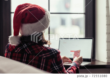 Back view of lonely european young woman wrapped in a plaid with with alarm clock sitting near window at cold winter day. Back view of lonely european young woman wrapped in a plaid with with alarm clock sitting near window at cold winter day. 72551080