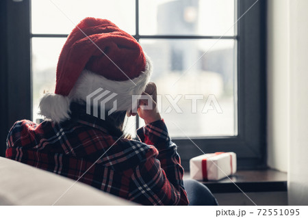 Back view of lonely european young woman wrapped in a plaid with with alarm clock sitting near window at cold winter day. Back view of lonely european young woman wrapped in a plaid with with alarm clock sitting near window at cold winter day. 72551095