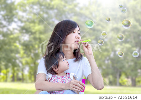 緑の樹木を背景に公園でシャボン玉で遊ぶ親子 72551614
