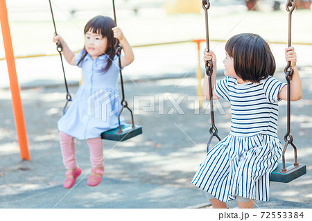 友達とブランコで遊ぶ女の子の写真素材