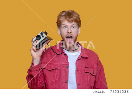 Red-haired bearded young man with old camera Red-haired bearded young man with old camera 72555588