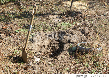 土に刺さったスコップと穴 72557059