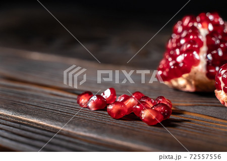 Craked ripe pomegranate on dark wooden background 72557556