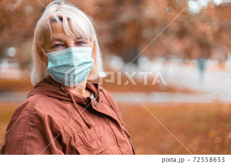 Coronavirus ,COVID-19 Pandemic. Blonde woman in wearing face mask protective for disease virus SARS-CoV-2 at the city street Coronavirus ,COVID-19 Pandemic. Blonde woman in wearing face mask protective for disease virus SARS-CoV-2 at the city street 72558653