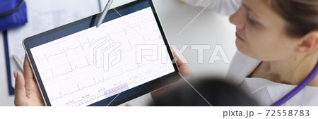 Doctors cardiologists looking at cardiogram on tablet and showing it with pen Doctors cardiologists looking at cardiogram on tablet and showing it with pen 72558783
