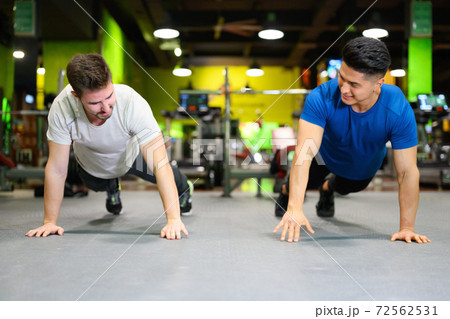 Two young men doing high planks in gym. Two young men doing high planks in gym. 72562531
