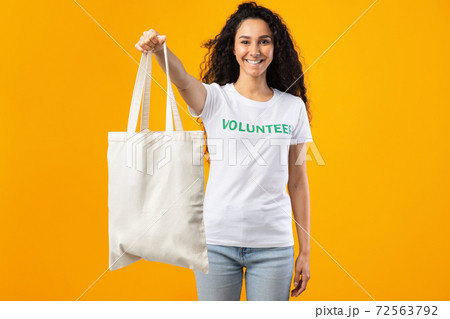 Volunteer Lady Showing White Eco Bag Standing Over Yellow Background Volunteer Lady Showing White Eco Bag Standing Over Yellow Background 72563792