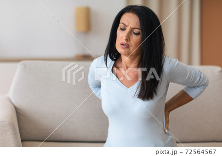 Mature lady having back pain while sitting on couch Mature lady having back pain while sitting on couch 72564567