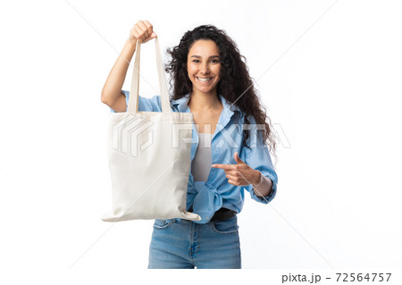 Woman Pointing Finger At Textile Bag Standing Over White Background Woman Pointing Finger At Textile Bag Standing Over White Background 72564757