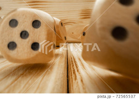 Wooden dice tossed on wooden background close up 72565537