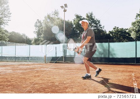 Middle-aged man playing tennis on outdoor tennis filed 72565721