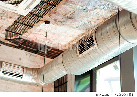 Ventilation system of the room installed on the ceiling of the building in a loft style close up of pipes with a grill. 72565782