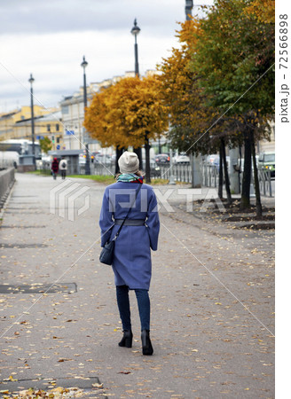 Woman walks on the asphalt with yellow leaves. 72566898
