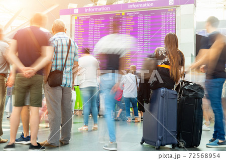Motion blurred travellers crowd looking at flight departure and arrival timetable at airport plane or train terminal. Travel and tourism concept. Flight delay cancellation. Covid-19 outbreak lockdown 72568954