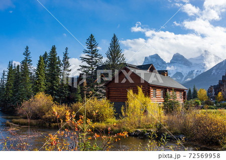 Canmore Opera House and Spring creek, clear blue sky snow capped The Three Sisters trio of peaks in the background. Town of Canmore in autumn season. Alberta, Canada. Canmore Opera House and Spring creek, clear blue sky snow capped The Three Sisters trio of peaks in the background. Town of Canmore in autumn season. Alberta, Canada. 72569958