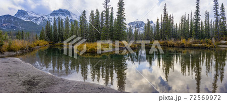 Snow capped Mount Lawrence Grassi mountain with blue sky and white clouds reflect on water surface in autumn. Beautiful natural scenery landscape at Canmore, Canadian Rockies, Alberta, Canada. 72569972