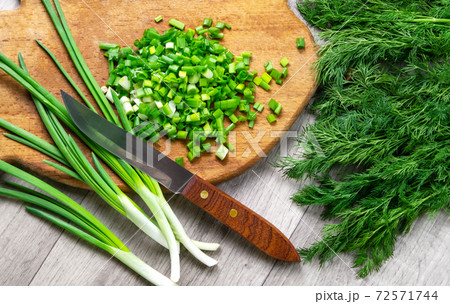 Finely chopped fresh green onions on an old wooden cutting board. Ingredient for salad. Home food concept. Natural food. top view 72571744