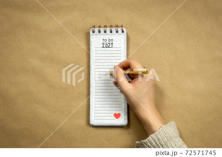 Top view 2021 human hand with notepad New year goals or planning on brown plain paper background, copy space modern design, business or school background 72571745