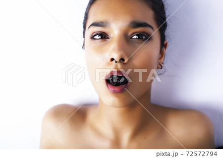 young pretty indian woman with dry fruit in mouth on white background 72572794