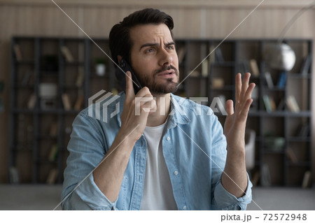 Unhappy man feel distressed talking on smartphone 72572948