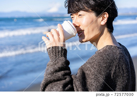旅行先の海岸でコーヒーを飲みながら寛ぐ男性 旅行先の海岸でコーヒーを飲みながら寛ぐ男性 72577030